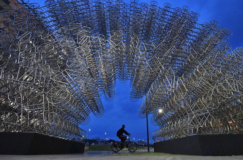 A man rides his bike past an art installation entitled "Forever Cycles" by Chinese artist Ai Weiwei in Rio de Janeiro, Brazil.  AFP