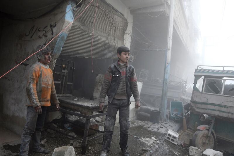 Children emerge from a shop after air strikes in the town of Saqba in the Eastern Ghouta region on February 8, 2018. Abdulmonam Eassa / AFP