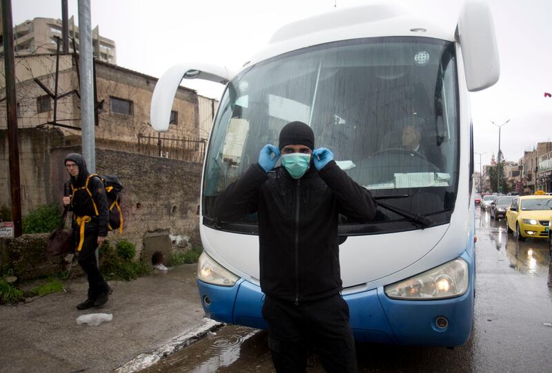 A Palestinian policeman stops tourist busses as preventive measures are taken against the coronavirus. AP