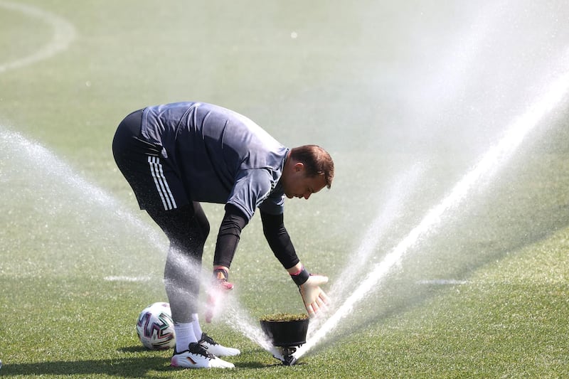 Goalkeeper Manuel Neuer washes his gloves during training. Getty