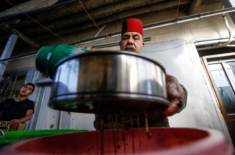 Ishaaq Kremed, a tamarind juice seller, filters pods of the fruit through a strainer at his home in Damascus. AFP
