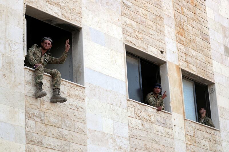 Turkey-backed Syrian rebel fighters gesture from a building in the town of Tal Abyad, Syria. Reuters
