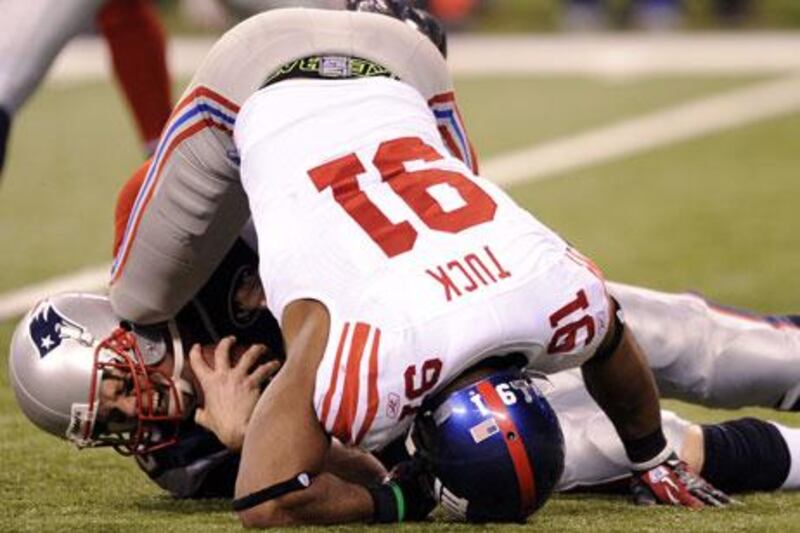 Patriots quarterback Tom Brady, left, is sacked by Giants' Justin Tuck on Sunday night.