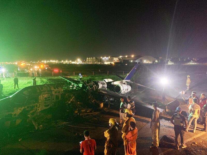 Investigators look on a burnt Lion Air aircraft at Manila's international airport.  EPA