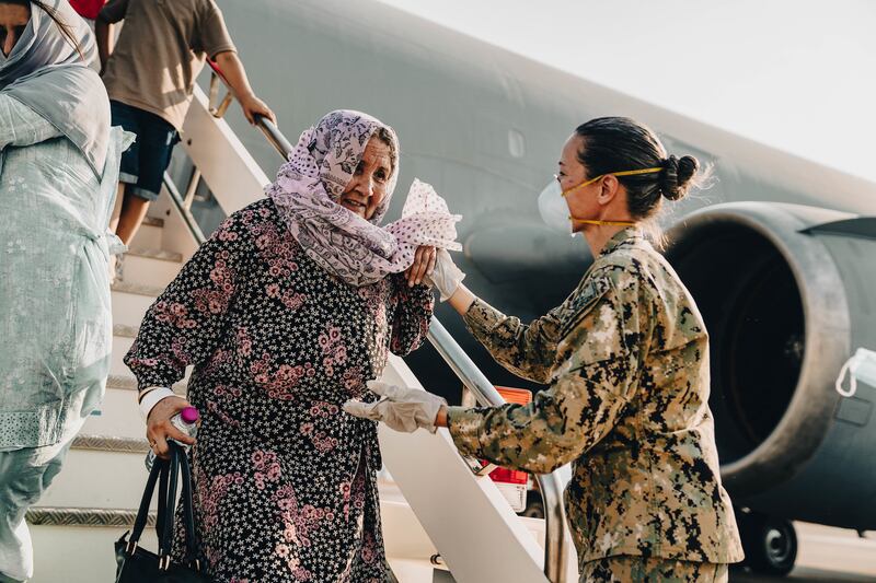 A command master chief assists an Afghan woman deplaning a US Air Force carrier in Sigonella, Italy. Photo: US Department of Defence