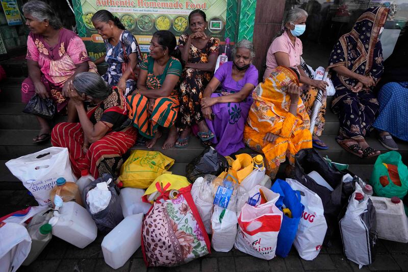 Women wait near an empty fuel station hoping to buy kerosene oil for cooking in Colombo, Sri Lanka. AP