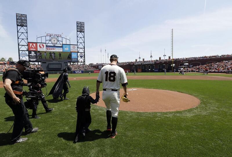 Miles Scott, second from right, dressed as Batkid, walks to the mound with San Francisco Giants pitcher Matt Cain (No 18) to throw the ceremonial first pitch before a home opener baseball game between the Giants and the Arizona Diamondbacks in San Francisco on Tuesday, April 8, 2014. Eric Risberg / AP