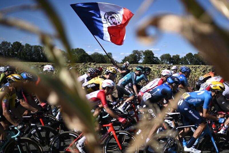 TOPSHOT - A man waves a French flag as the peloton passes by. AFP