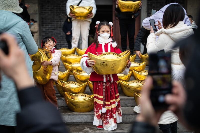 A girl holds a model of a gold ingot in Expo Garden, Wuhan. Getty