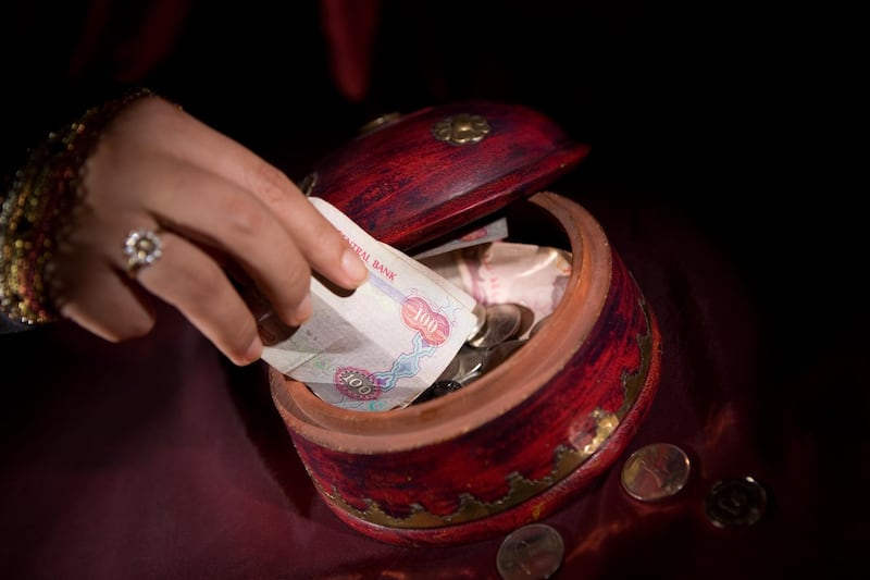 An arab woman putting money into a box.