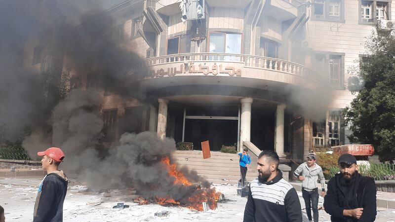 Smoke rises near a building as people take part in a protest in Sweida, southern Syria. Reuters