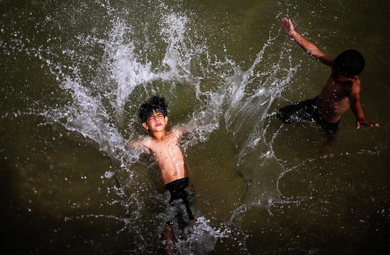 Two Palestinian brothers Mamud, 10, left, and Wassem, 8, Reasha, right, enjoy their time in the Gaza beach during a hot weather in the west of Gaza City. Mohammed Saber / EPA