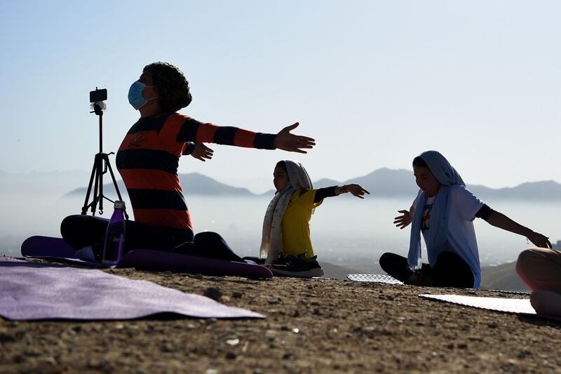 Women perform a yoga posture as they take part in a yoga session at Shahrak Haji Nabi hilltop on the outskirts of Kabul in Afghanistan. AFP