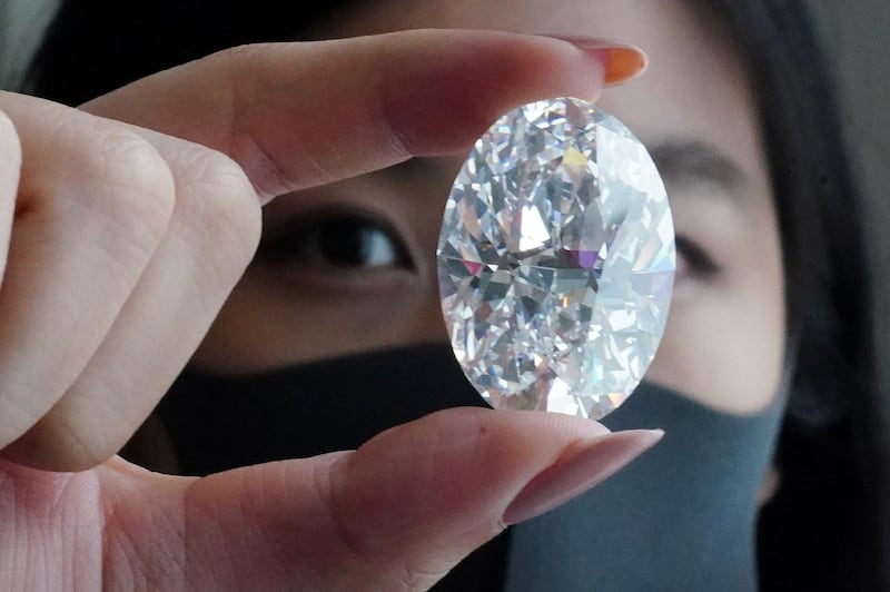 An employee of Sotheby's poses with a perfect 100+ carat diamond, the second largest oval diamond of its kind to ever appear at an auction which will be auctioned by Sotheby's in Hong Kong in October, in the Manhattan borough of New York City, New York, U.S., September 9, 2020. Picture taken September 9, 2020. REUTERS/Carlo Allegri