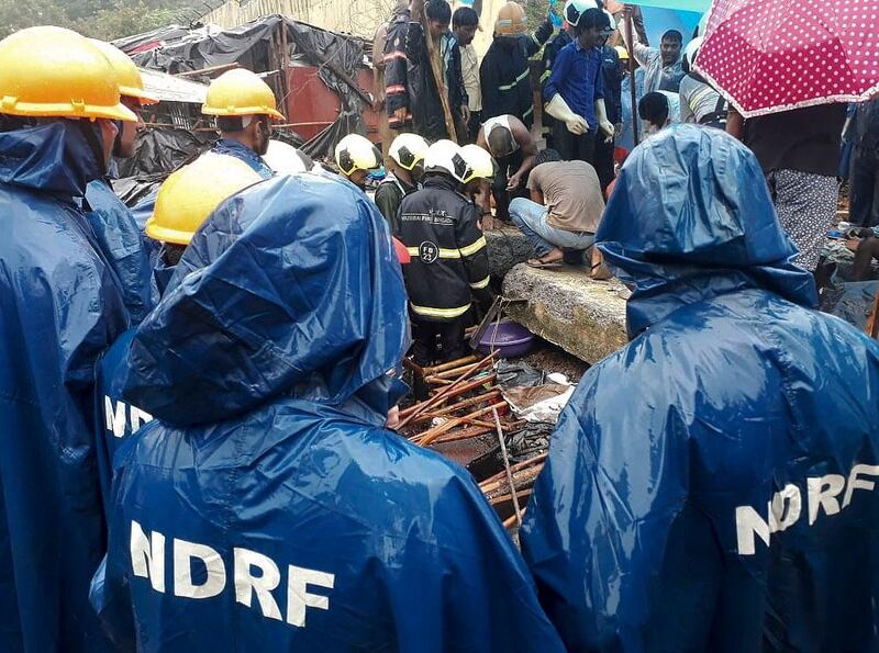 Rescuers of the National Disaster Response Force (NDRF) stand at the spot after heavy rainfall caused a wall to collapse onto shanties, in Mumbai. AP Photo