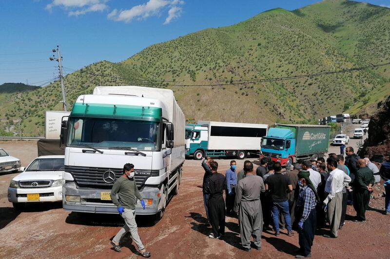 People gather near trucks after the border between Iraqi Kurdistan and Iran partially reopened for the first time since the outbreak of the coronavirus, at the border in Iraq's Halabja Province. Reuters