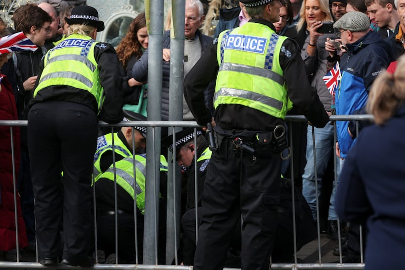 Police officers restrain the egg-thrower amid the crowd gathered to see King Charles. Reuters