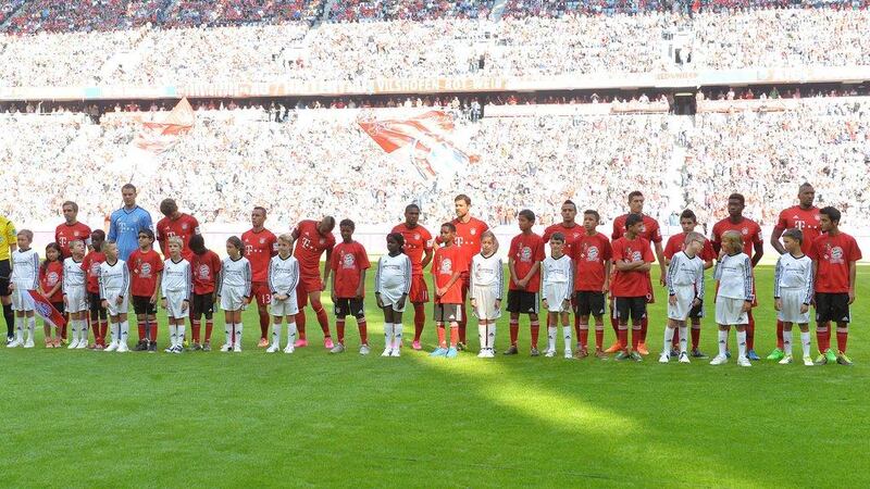 Bayern Munich players stand with refugee children on the pitch prior to the Bundesliga match against Augsburg on Saturday. Kerstin Joensson / AP / September 12, 2015 