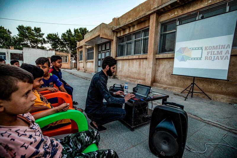 A member of Syrian-Kurdish filmmaker Shero Hinde's mobile cinema "Komina Film" initiative prepares a laptop connected to a projector and screen for a film screening for children at a school yard in the village of Shaghir Bazar, 55km southest of Qamishli in the Kurdish-populated areas of northeastern Syria's Hasakeh province. AFP