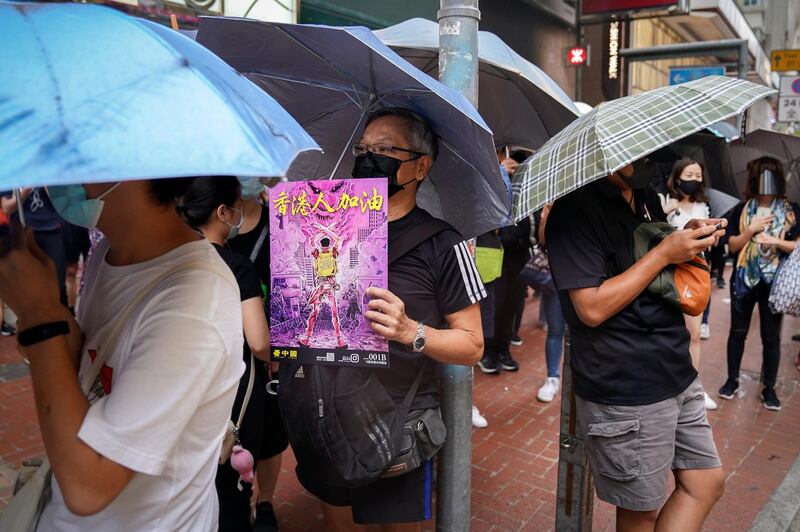 A man wears a mask holding a poster which reads "Go Hong Kong people". AP Photo
