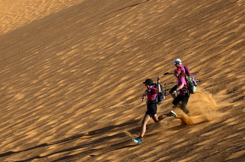 Women run down a sand dune as they take part in the desert trek, the Rose Trip Maroc. AFP