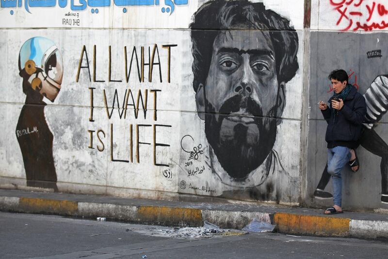 An Iraqi man leans on a wall bearing murals inspired by ongoing anti-government demonstrations in the capital Baghdad's Tahrir square on January 14, 2020. AFP