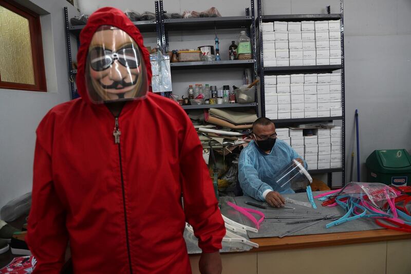 An inmate models the protective gear inmates manufacture as fellow inmate Luis Huaman makes face shields at a workshop in the Lurigancho prison, on the outskirts of Lima, Peru. AP Photo