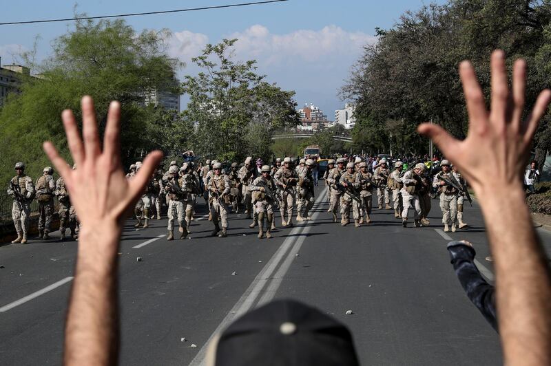 A demonstrator holds up his hands toward advancing soldiers during a protest as a state of emergency remains in effect in Santiago, Chile. AP