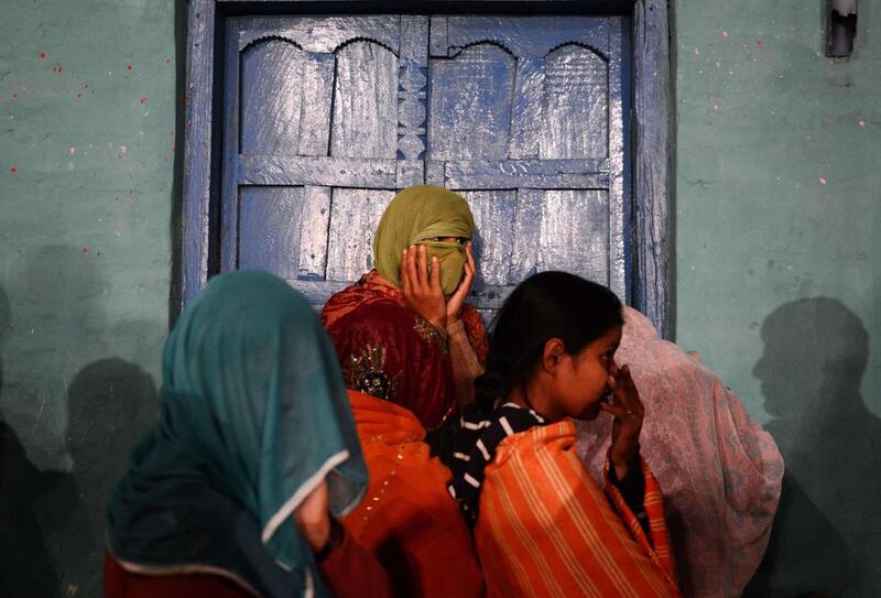 Indian revellers wait outside their home to watch a Hindu priest exit a nearby temple. Chandan Khanna / AFP 
