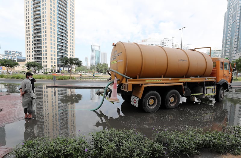 Workers clear a flooded road in Al Barsha heights. Pawan Singh / The National