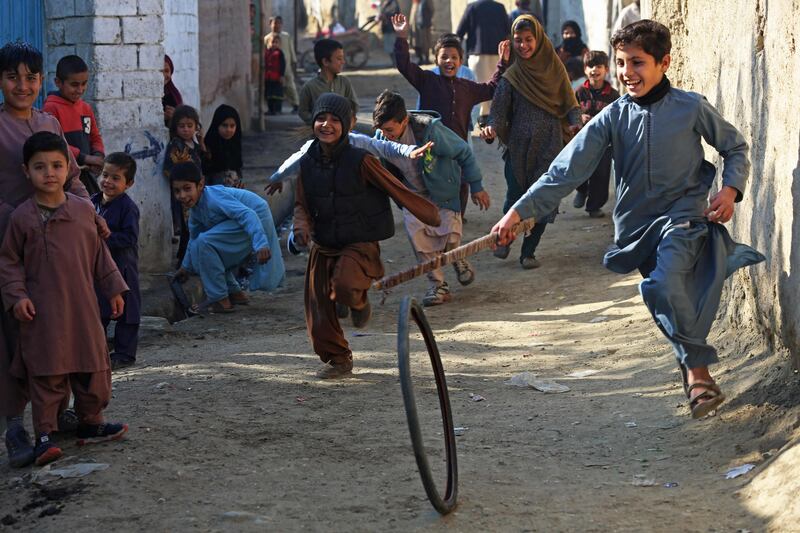 Afghan children play with a tyre on a street in Jalalabad. AFP