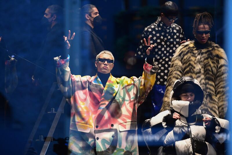 Models presenting creations for Dolce & Gabbana's Men's autumn/winter 2022/2023 fashion collection gesture from behind a venue's glass door for the public outside who couldn't get in. AFP