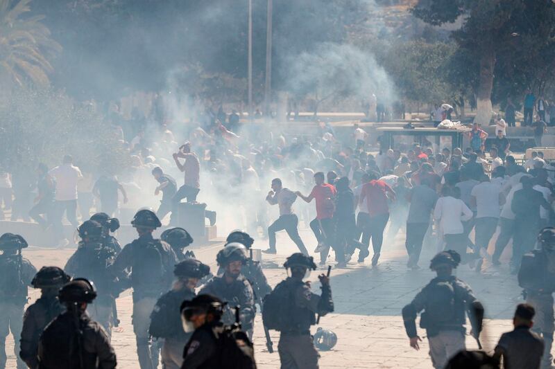 Palestinians run for cover from sound grenades at the Al Aqsa Mosque compound as clashes broke out during the overlapping Jewish and Muslim holidays of Eid Al Adha and the Tisha B'av. AFP