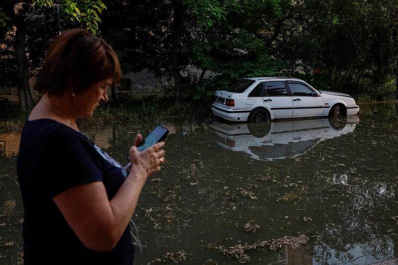 A resident uses her phone along a flooded street in Kherson. Reuters