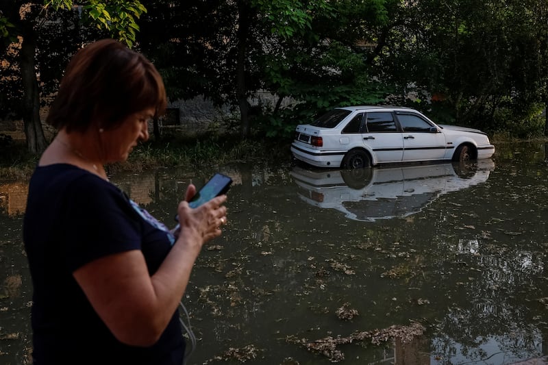 A resident uses her phone along a flooded street in Kherson. Reuters