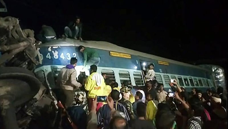 People and rescuers look for passengers in the derailed train in Kuneru, southeast India. NNIS TV / AFP