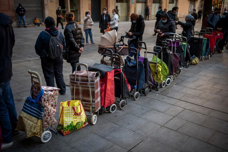 Shopping trollies lined up next to their owners, waiting their turn to receive a weekly pack of donated food and supplies, outside a church in Barcelona. AP Photo