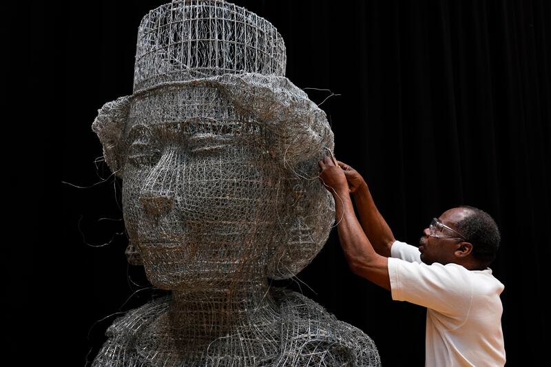 Artist Carl Gabriel works on a sculpture made of wire depicting the head of Britain's Queen Elizabeth II. AP Photo 