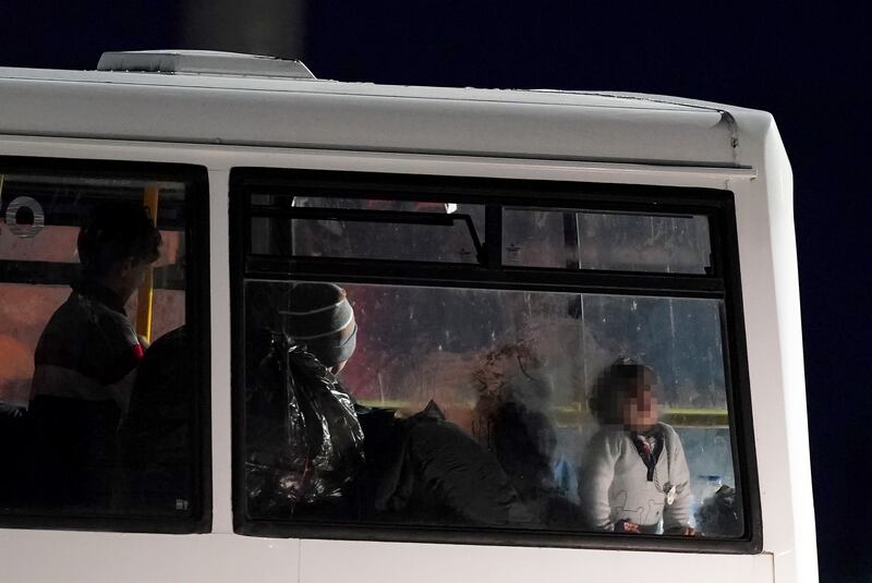 A group of people thought to be migrants wait to be transported onboard a bus after being brought into Dover.