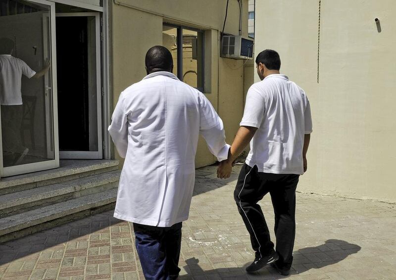 Teacher Honest Ncube (left) holds a teenager by his arm as they return to the classroom at the Dubai Autism Centre. Jaime Puebla / The National