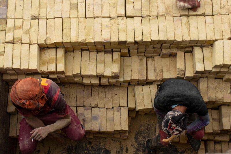 Workers take a cigarette break as they stack bricks at the factory.  AFP