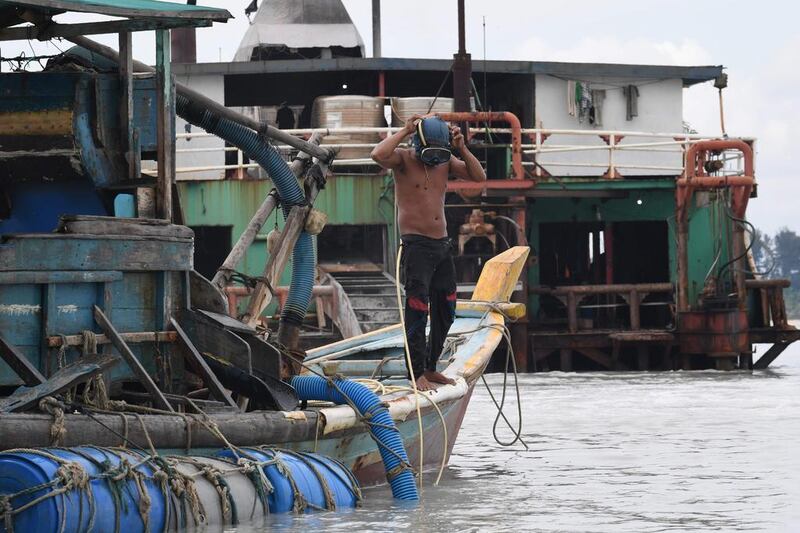 Illegal miner Paci adjusting his mask as he prepares for a dive to dredge tin from the seabed off Sungai Liat in northeast Bangka. One-third of the world's tin comes from the Indonesian islands of Bangka and Belitung, where thousands risk serious injury and death in the mines. Goh Chai Hin / AFP

