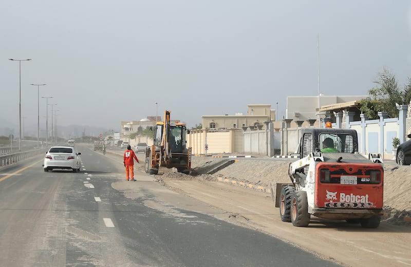 Workers clearing mud from the roads in Kalba. Pawan Singh / The National 