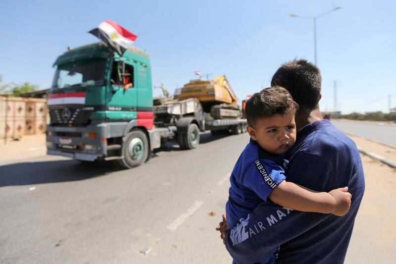 A man carrying a boy watches the convoy arrive in southern Gaza. Another 17,000 homes were damaged in the air strikes. Reuters