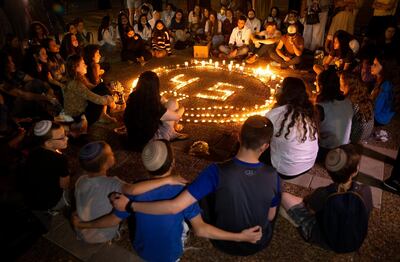 FILE - In this Sunday, May 2, 2021 file photo, people gather around candles during a vigil in memory of the 45 ultra-Orthodox Jews killed in a stampede at a Lag BaOmer festival at Mount Meron in northern Israel on Friday, in Tel Aviv, Israel. Israel's government watchdog agency said Monday that it will launch an investigation into the deadly stampede at the religious festival over the weekend. (AP Photo/Oded Balilty, File)