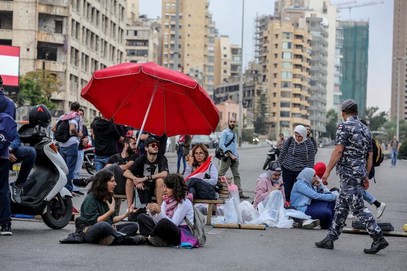 Protesters sit on the ground as they block the main highway leading to east Beirut during ongoing anti-government protests in Beirut, Lebanon. EPA