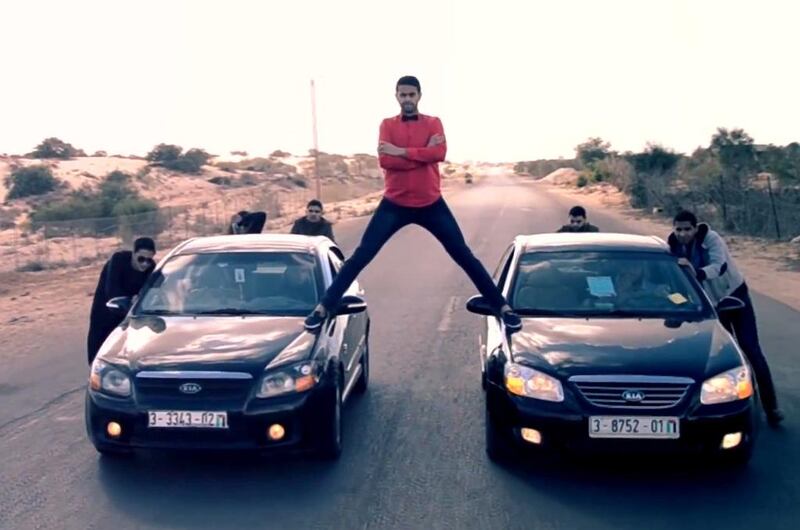 Video stills from the Tashwesh Comedy Troupe spoof of a Jean Claude Van Damme ad for Volvo show a man standing on two cars being pushed down a motorway by several other men.  Courtesy Tashwesh Comedy Troupe