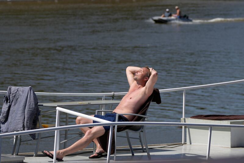 A man enjoys the sun on his boat on the river Thames near Hammersmith in London. AP