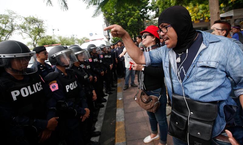 A Thai pro-democracy protester shouts at police officers during a gathering marking the fourth anniversary of the military take-over of government in Bangkok. Sakchai Lalit / AP Photo