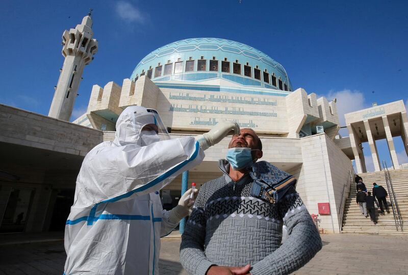 A member of the Jordanian health ministry's epidemiological investigation team, takes a random nasal swab to test for COVID-19, from a man leaving the King Abdullah I mosque following the Friday noon prayers, in the capital Amman, on December 18, 2020. (Photo by Khalil MAZRAAWI / AFP)